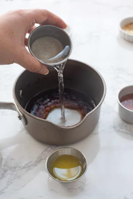 pouring water and soy sauce into a saucepan