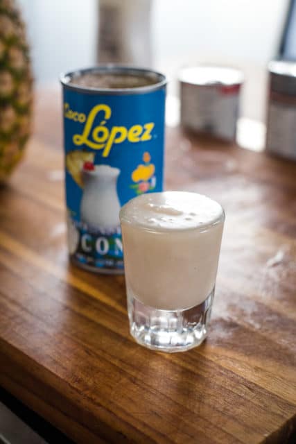 picture of shot glass of coconut cream with coco lopez can in the background